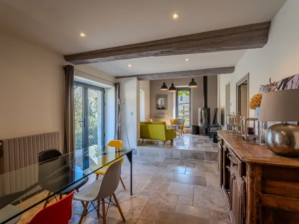 Salle à manger ouverte sur le salon, poutres apparentes.