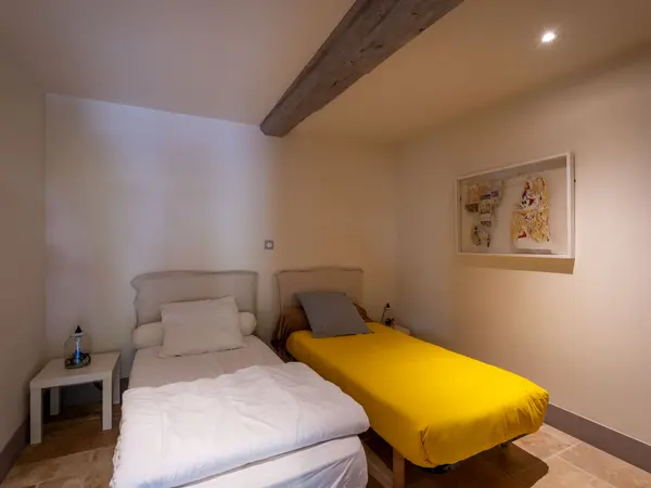 Chambre à deux lits simples sous poutre apparente.