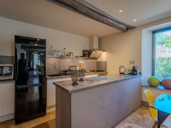 Cuisine ouverte avec îlot central et poutre apparente.