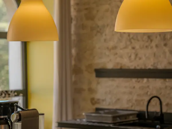Cuisine, suspensions lumineuses et mur en pierre.