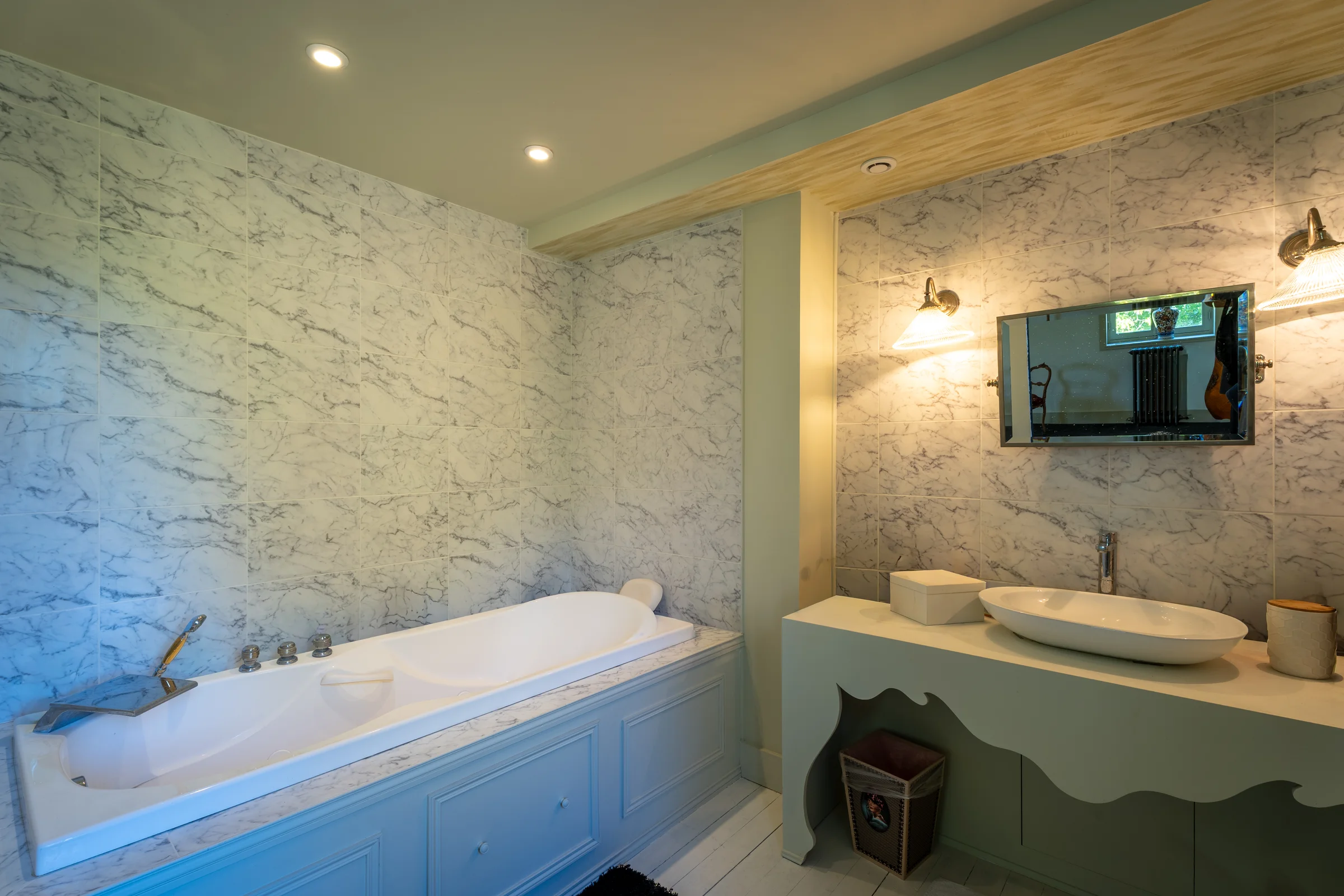 Salle de bains avec baignoire encastrée et parois marbrées.