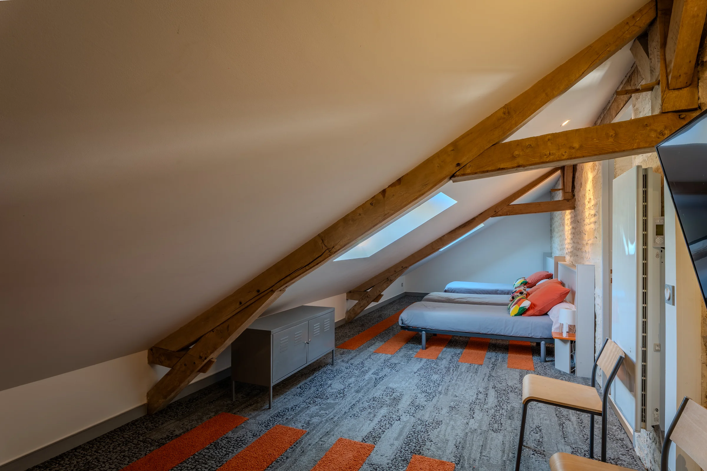 Chambre dortoir sous combles avec charpente apparente et Velux.