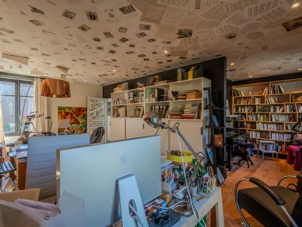 Poste de travail et bibliothèque sous un plafond habillé de pages imprimées.