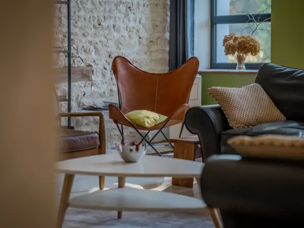 Salon, fauteuil en cuir et mur en pierre apparente.