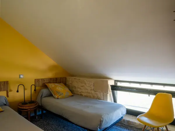 Détail d'un lit dans la chambre aux murs jaunes.