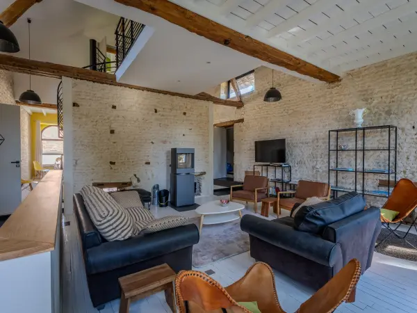 Salon avec escalier en colimaçon et mezzanine, poêle à bois.