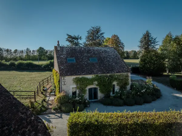 Vue aérienne du petit gîte entouré de jardin et de prairie.