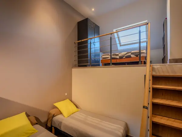 La chambre à deux lits avec mezzanine et escalier en bois.
