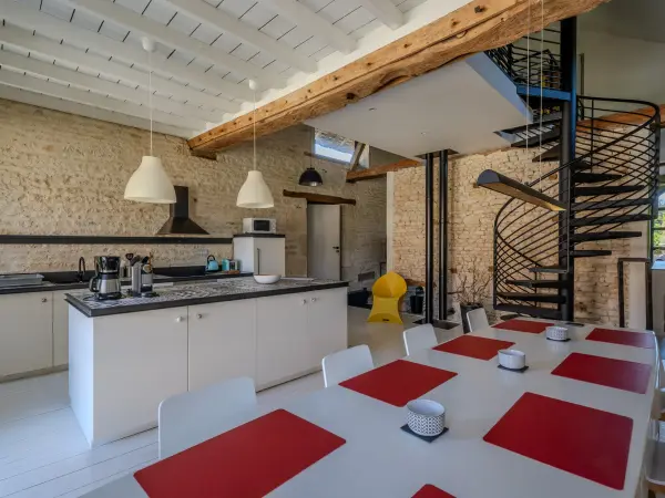 Cuisine ouverte et salle à manger sous charpente, avec escalier en colimaçon.