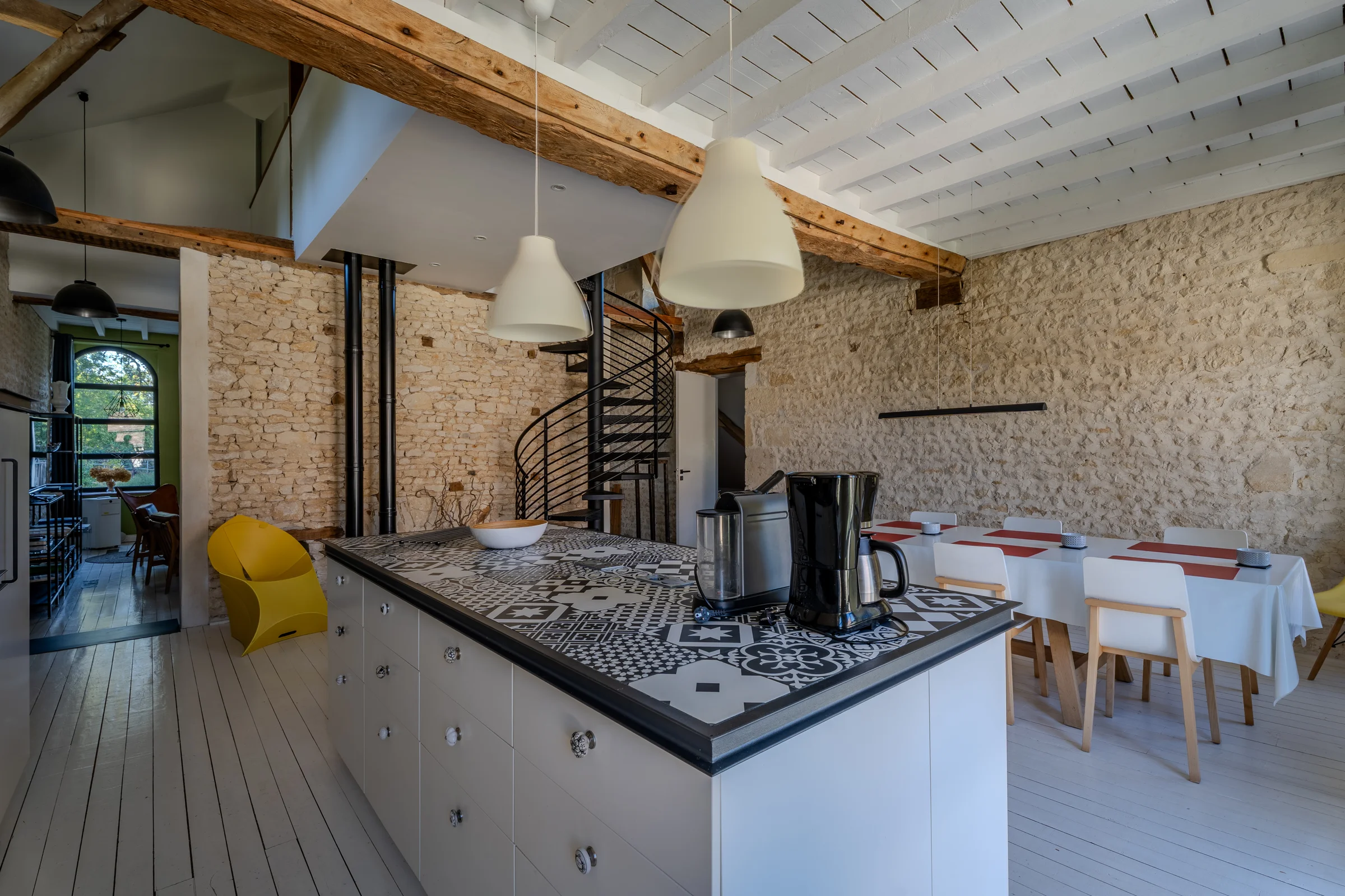 Pièce de vie avec îlot de cuisine, escalier en colimaçon et salle à manger.