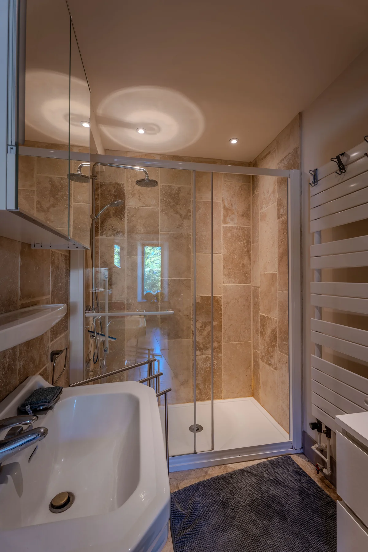 Douche vitrée et travertin dans la salle de bains.