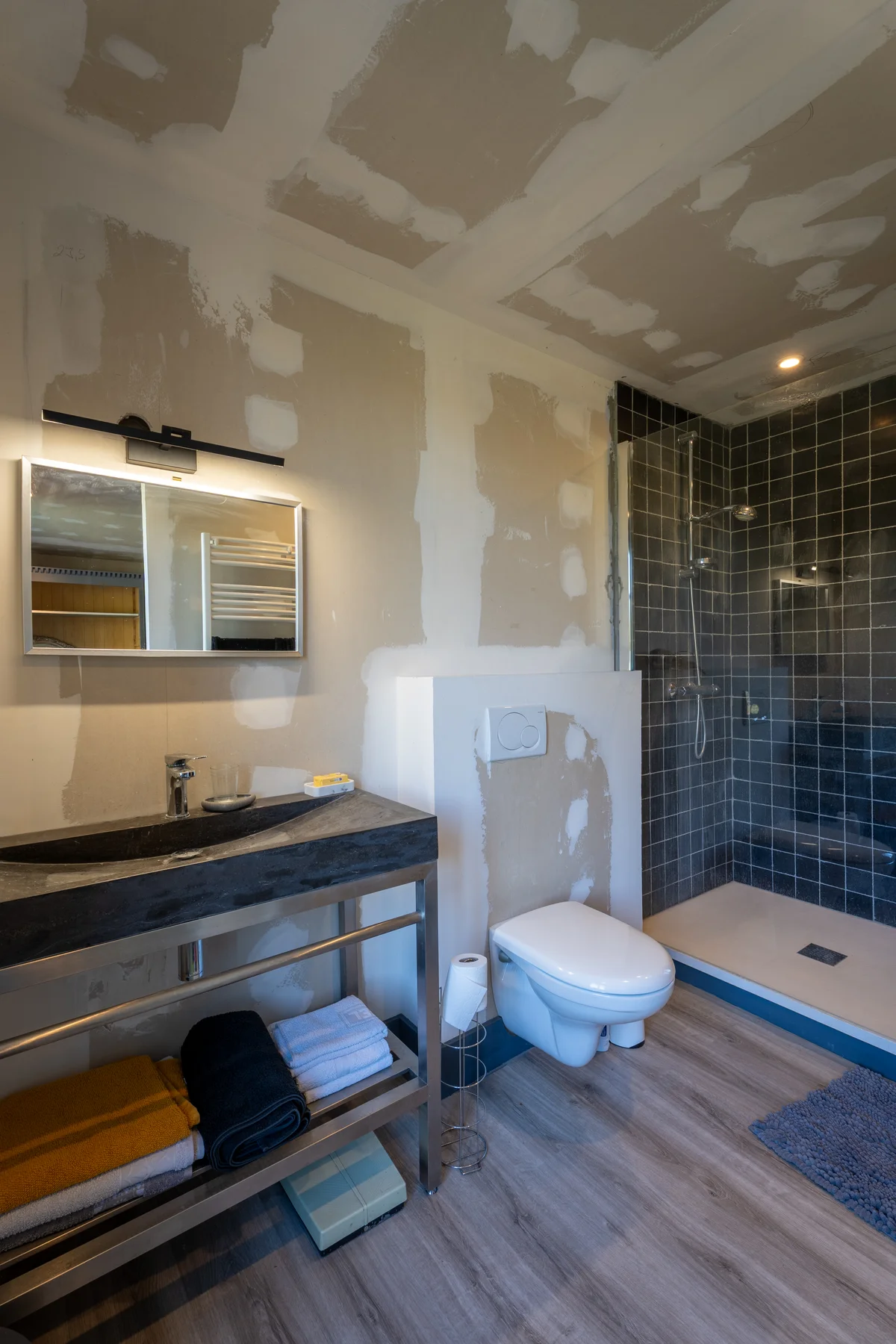 Salle de bains, douche carrelée et vasque noire.