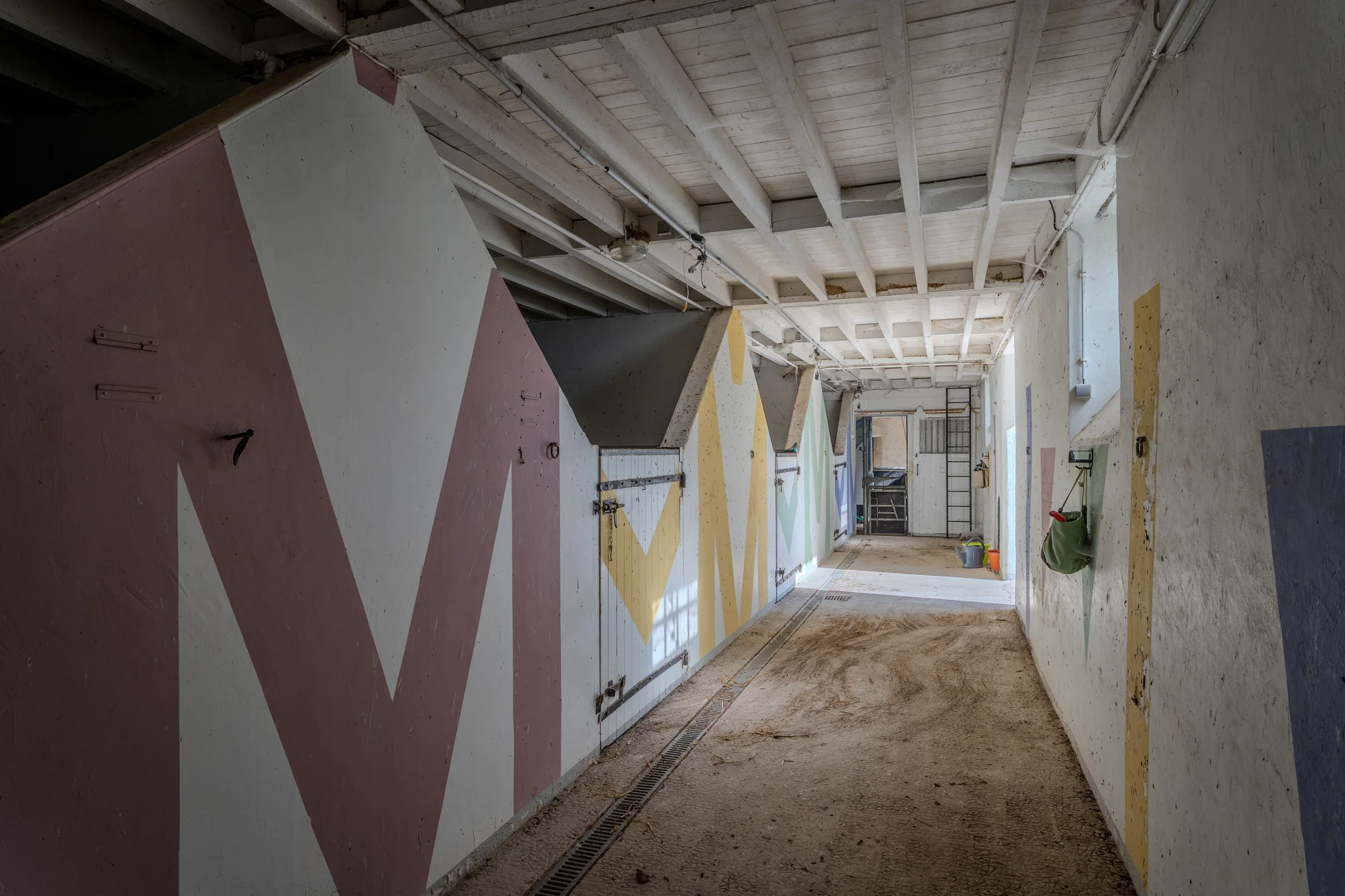 Couloir de distribution des box, décoration peinte aux murs.