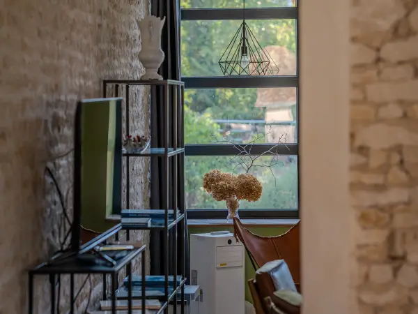 Salon, mur en pierre et baie vitrée sur le jardin.