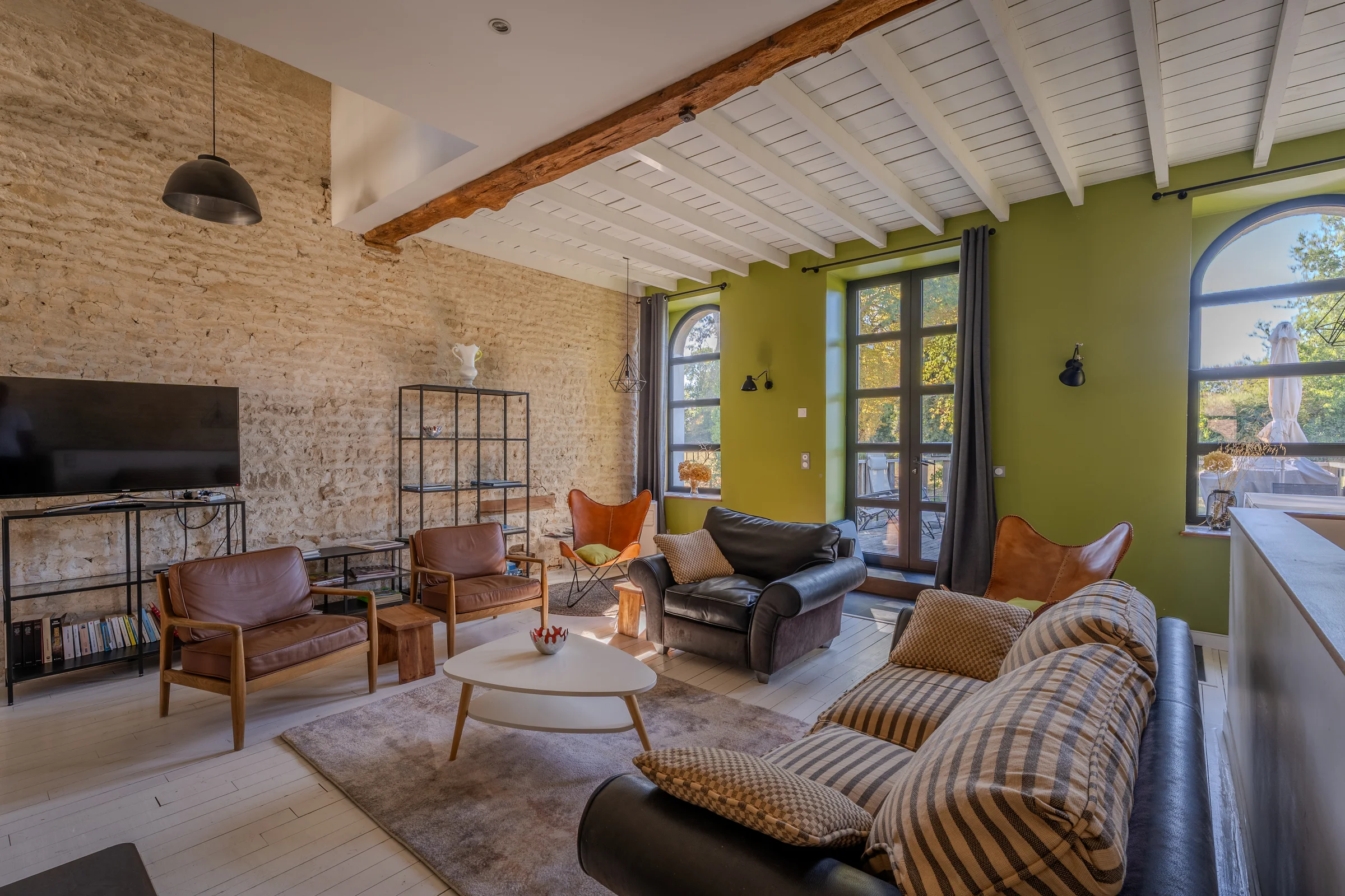 Salon avec pierre apparente et fauteuils colorés.