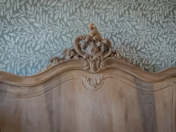 Détail sculpté d'une tête de lit en bois.