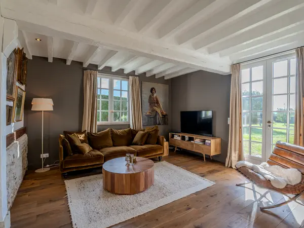 Le salon aux poutres blanchies, ouvert sur le jardin par de larges baies vitrées.