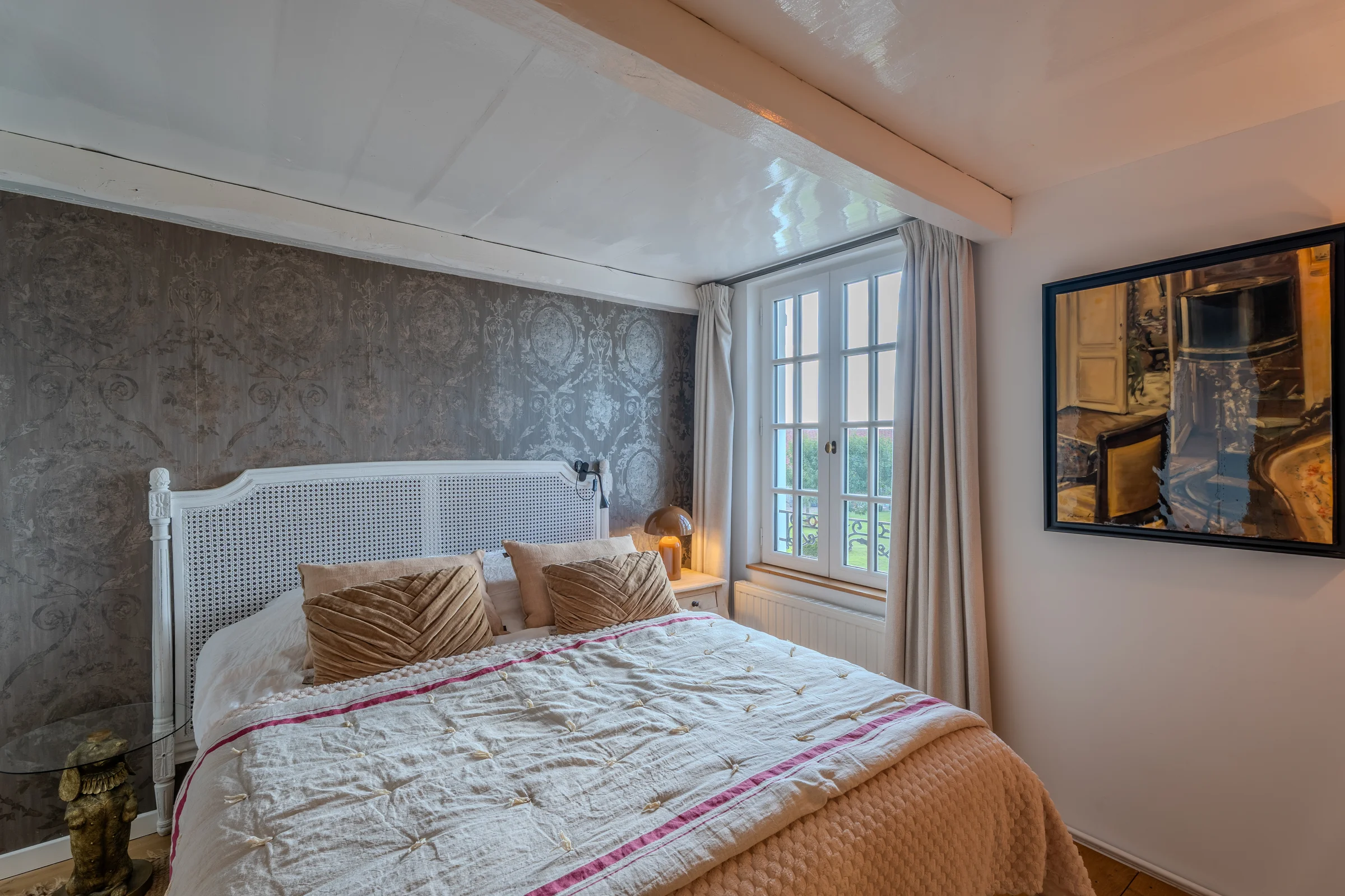 Chambre, tête de lit cannée et poutre apparente.