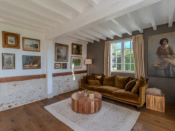 Le salon aux murs rythmés par la pierre apparente et les poutres blanchies.