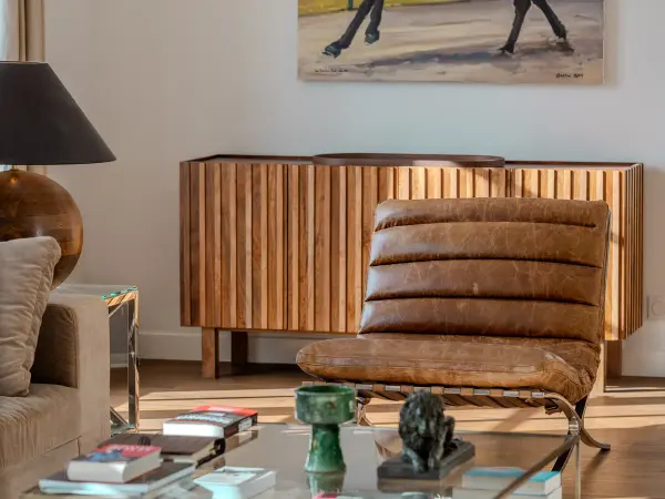 Salon avec enfilade en bois et fauteuil en cuir.