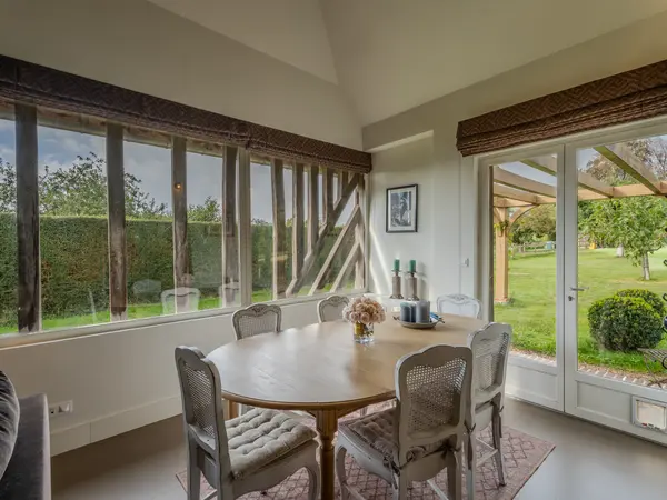 Salle à manger vitrée ouvrant sur le jardin, structure bois apparente.