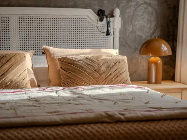 Chambre, tête de lit cannée et papier peint à motifs.