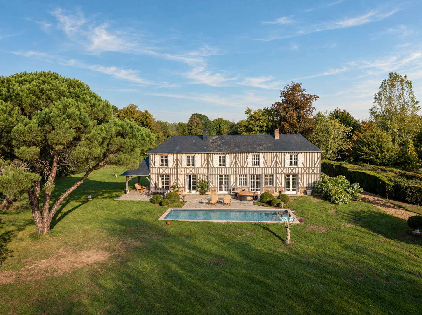 Vue aérienne de la maison principale et de son jardin arboré avec piscine.