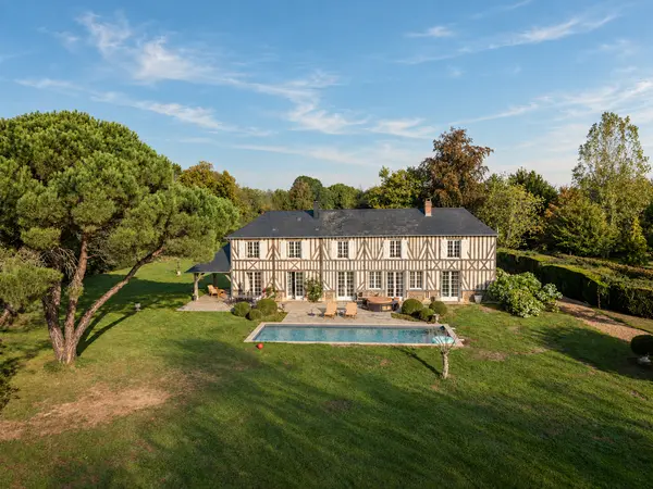 Vue aérienne de la maison principale et de son jardin arboré avec piscine.