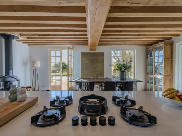 Îlot de cuisine équipé sous charpente apparente, avec vue vers l'espace repas.