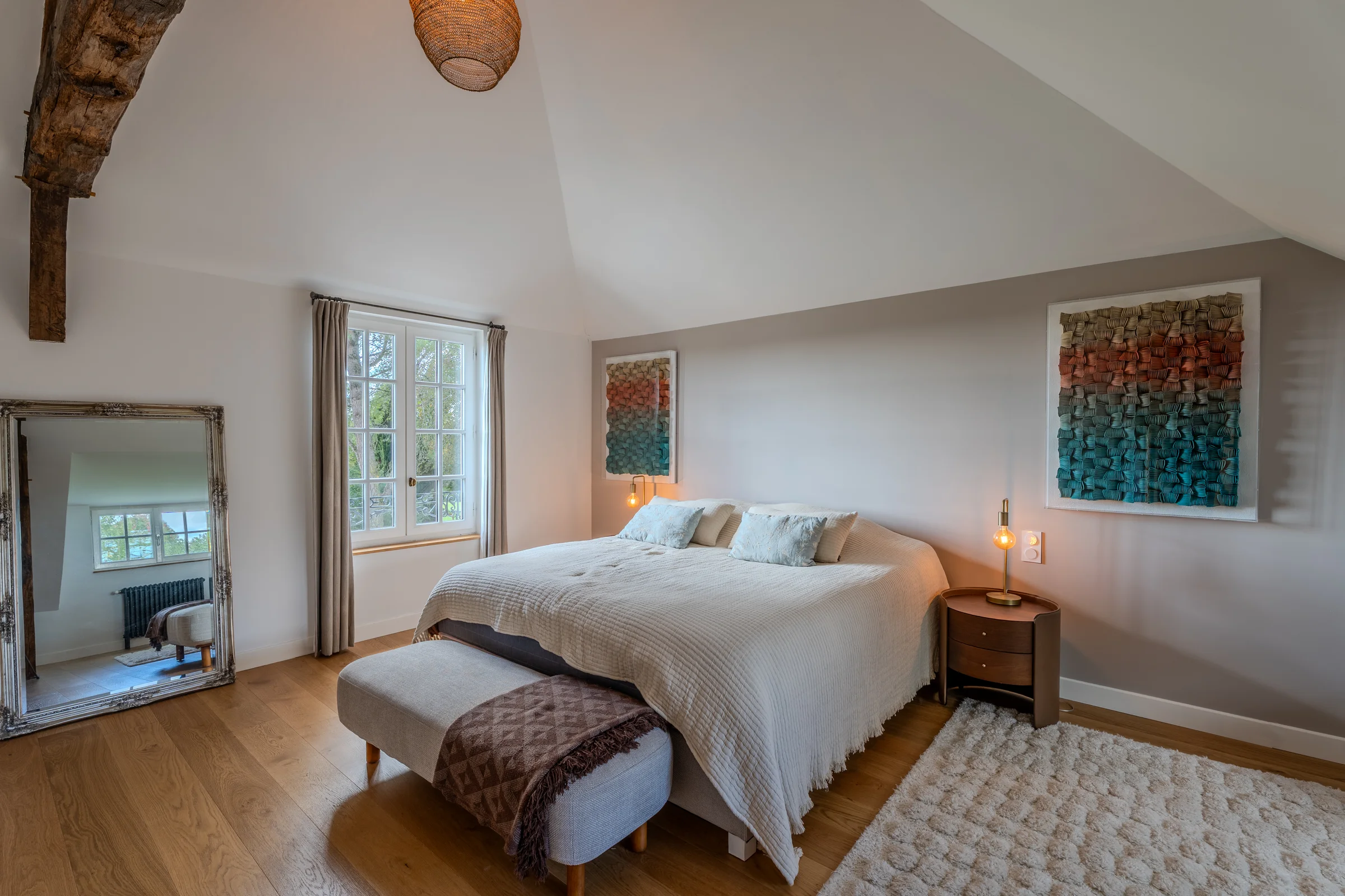Chambre sous charpente, lumière naturelle et vue sur le jardin.
