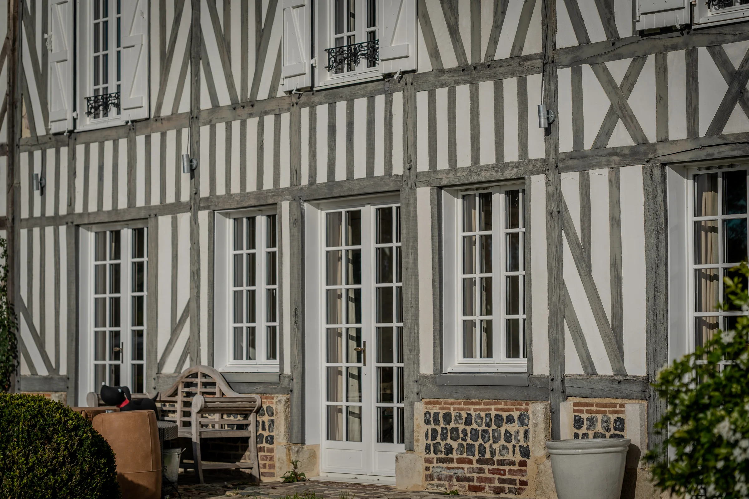 Façade à pans de bois, portes-fenêtres et soubassement en pierre et brique.