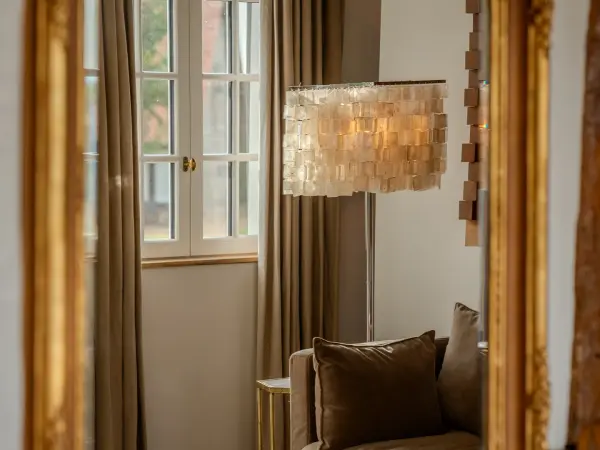 Reflet dans un miroir doré d'un coin salon et d'une fenêtre.