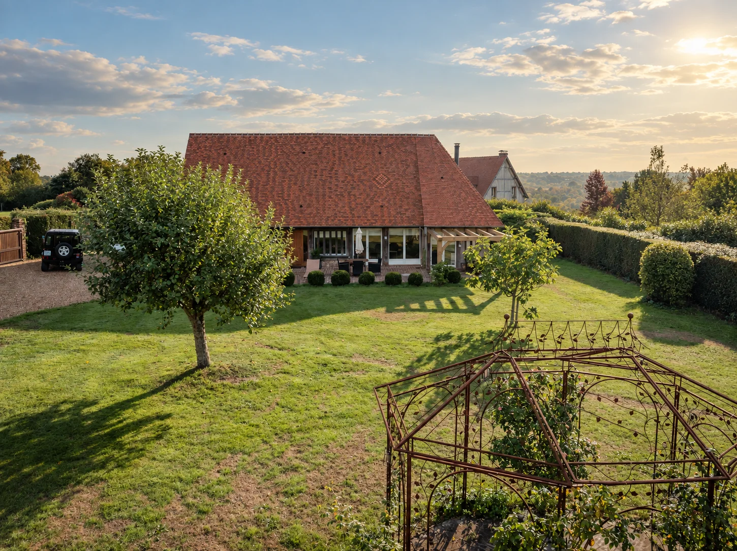 Maison d'amis sous toiture de tuile, vue au crépuscule depuis le jardin.