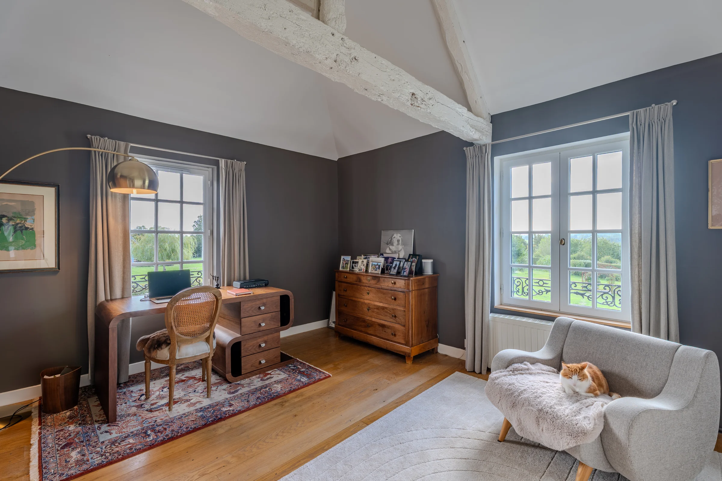 Chambre sous charpente avec coin bureau et double vue sur la campagne.