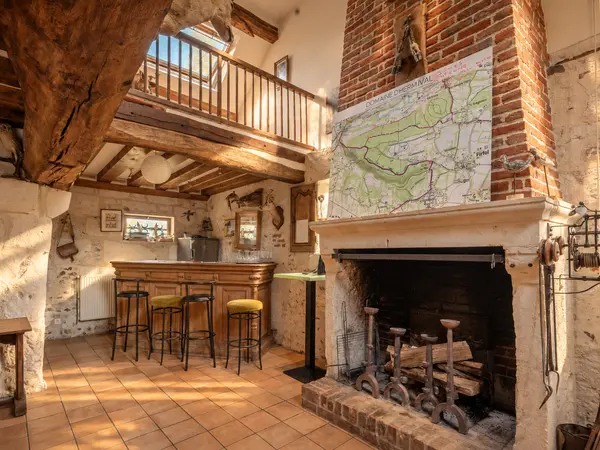 Cheminée et bar sous mezzanine, carte du domaine affichée.