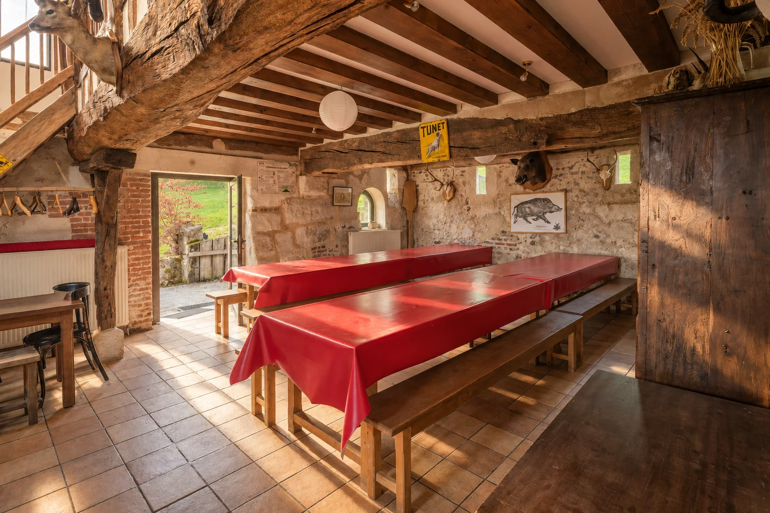 Salon-salle à manger avec tables et bancs en bois.