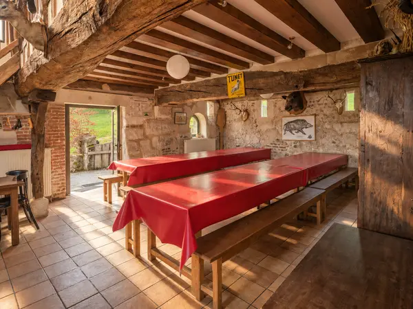 Salon-salle à manger avec tables et bancs en bois.