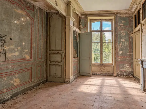 Chambre à alcove du 18e siècle avec grande fenêtre donnant sur le parc, boiseries anciennes et cheminée en marbre.