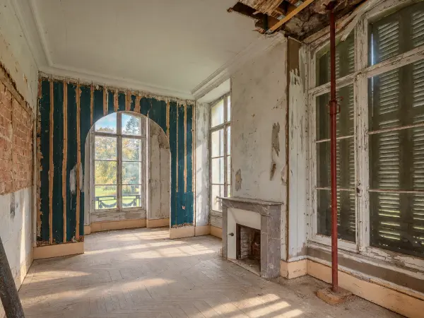 Chambre en restauration, arche vitrée et cheminée en marbre.