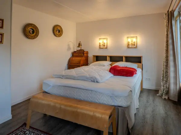 Chambre, lit double et tête de lit en bois clair.