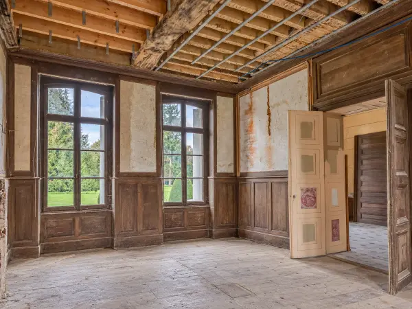 Salle à manger en chantier, solivage apparent et lambris conservé.