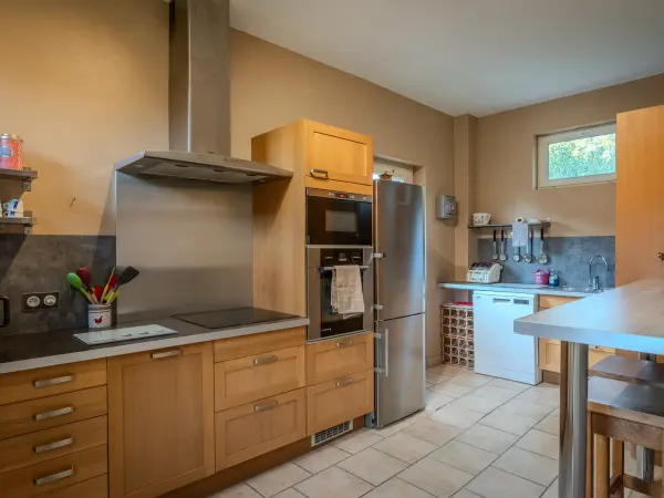Cuisine équipée, meubles en bois clair et électroménager encastré.