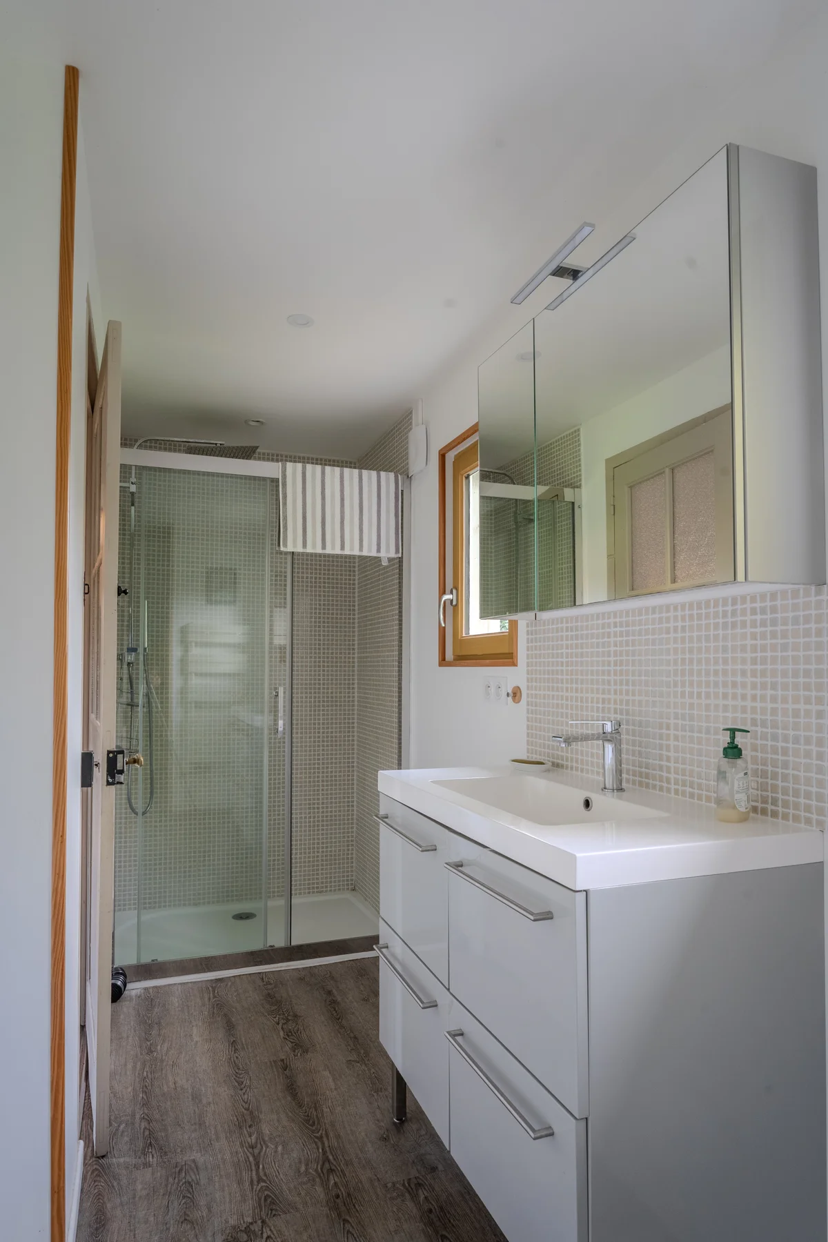Salle de bains, douche vitrée et vasque simple.