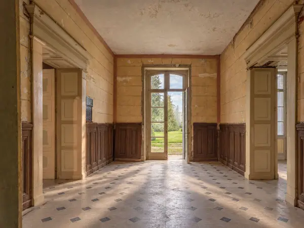 Entrée traversante, sol en cabochon et porte-fenêtre ouvrant sur le parc.