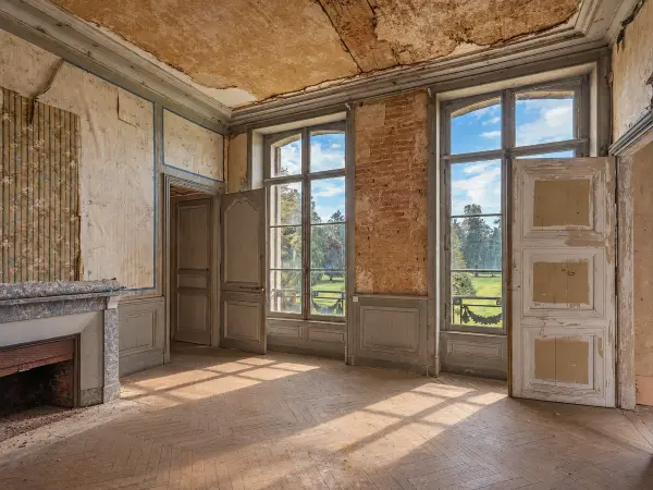 Chambre aux fenêtres hautes ouvrant sur le parc, cheminée en marbre d'aspect.