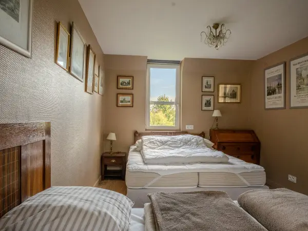Chambre mansardée, fenêtre centrale et mobilier en bois.