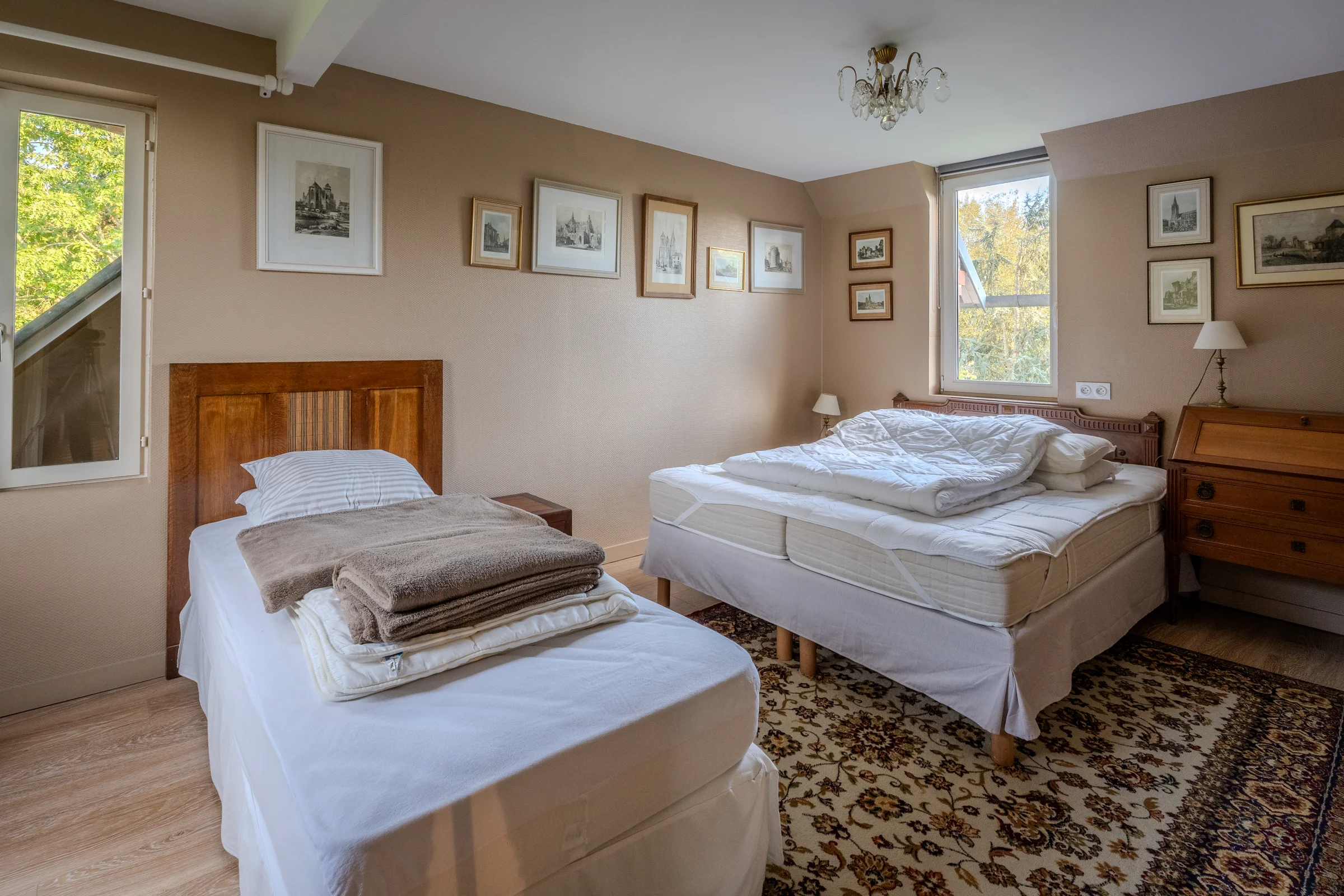 Chambre à deux couchages, parquet et fenêtre sur jardin.