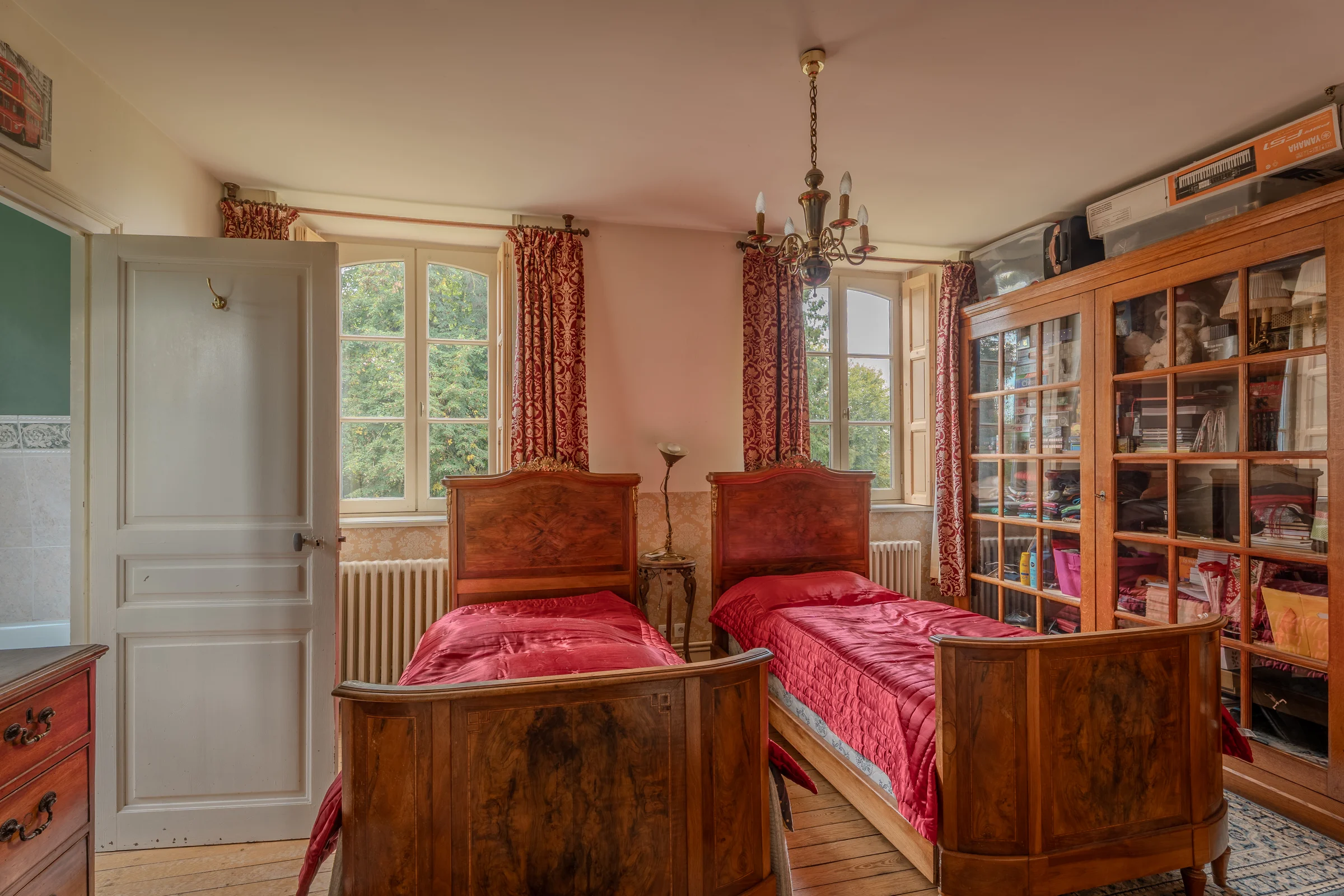 Chambre à deux lits, fenêtres hautes et bibliothèque d'appui.