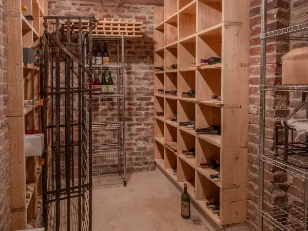 Cave à vins, casiers en bois sur mur de brique.