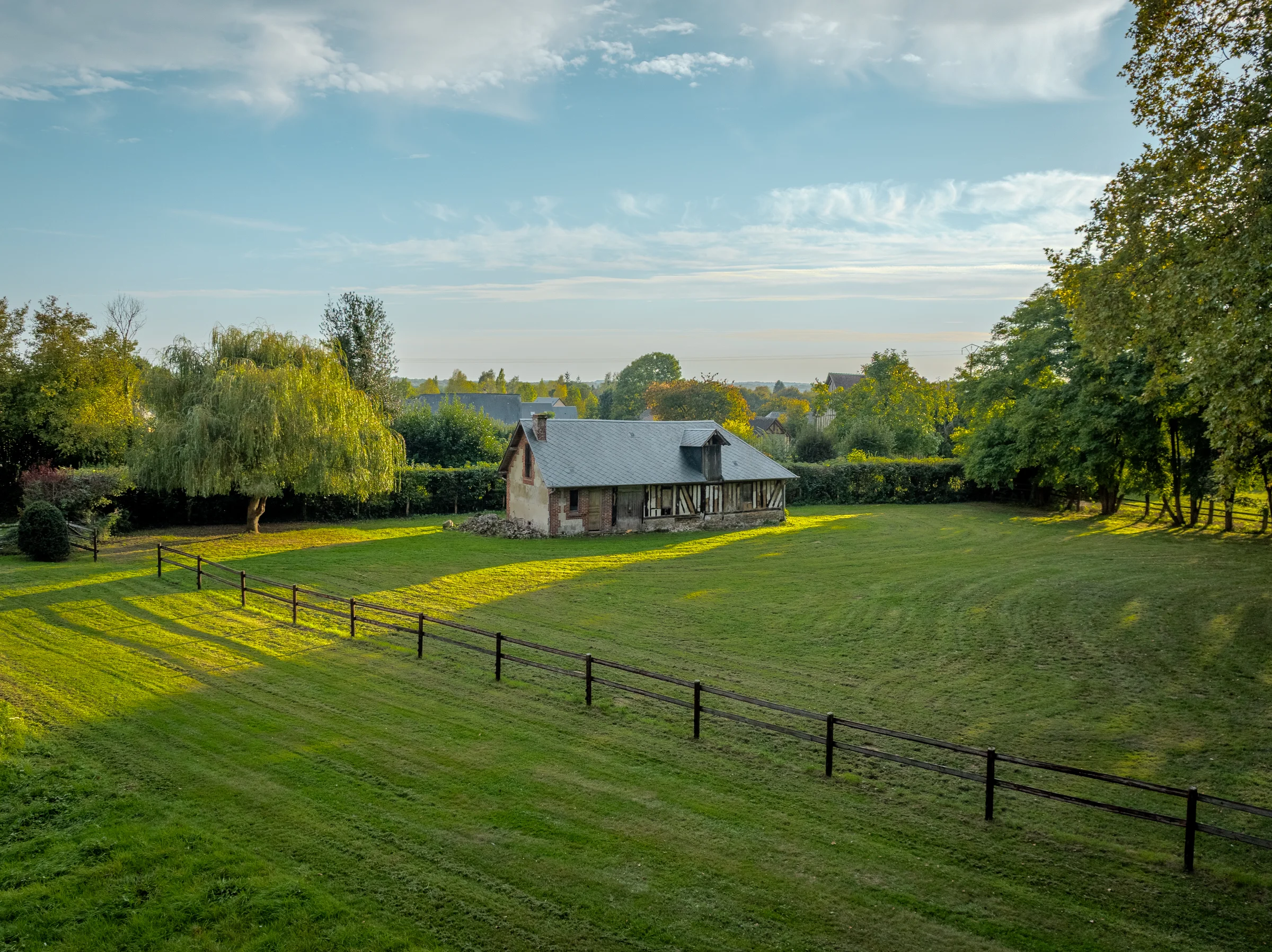 Vue aérienne d'une bergerie isolée dans une prairie clôturée.